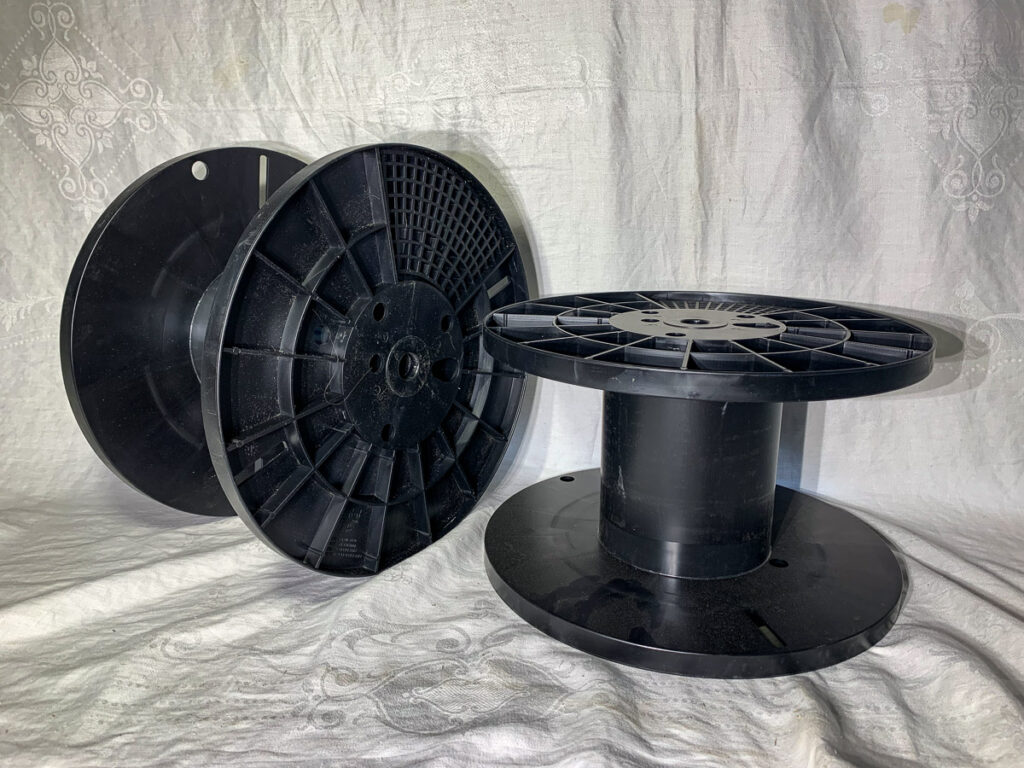 Two black empty spools for poly wire electric fence wire.